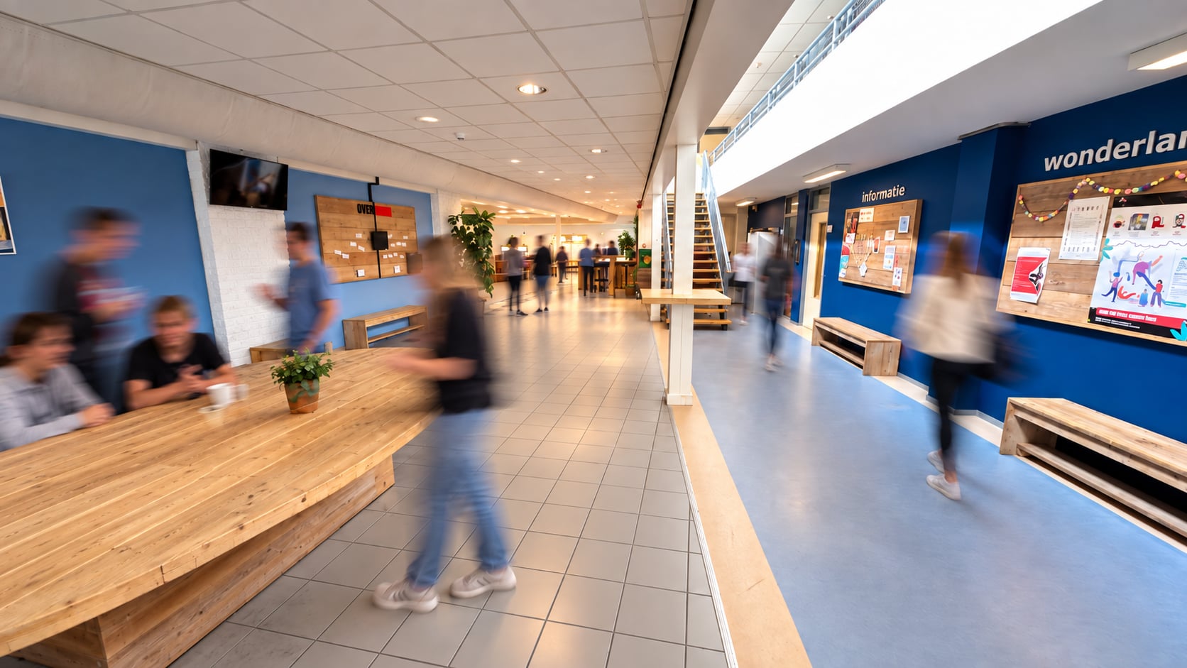 De ontmoetingsruimte van Z1 Verhuur in bedrijf: gasten rond de lange houten tafels en in de centrale hal